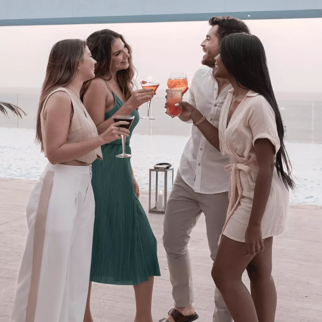 Grupo de amigos brindando con cócteles junto a una piscina.