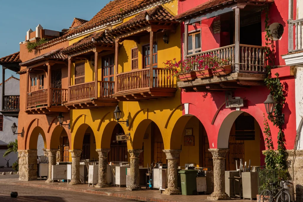 Fachadas vibrantes de edificios coloniales con balcones de madera y arcos, bajo un cielo azul claro.